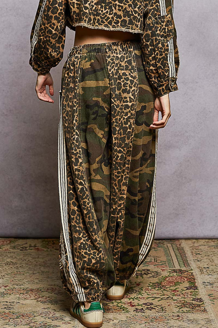 Person wearing a leopard print top and camouflage pants with white stripes on a textured floor.