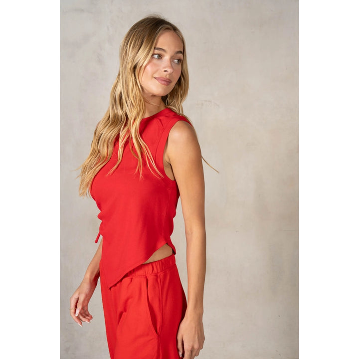 Woman wearing a red sleeveless top and pants against a neutral background
