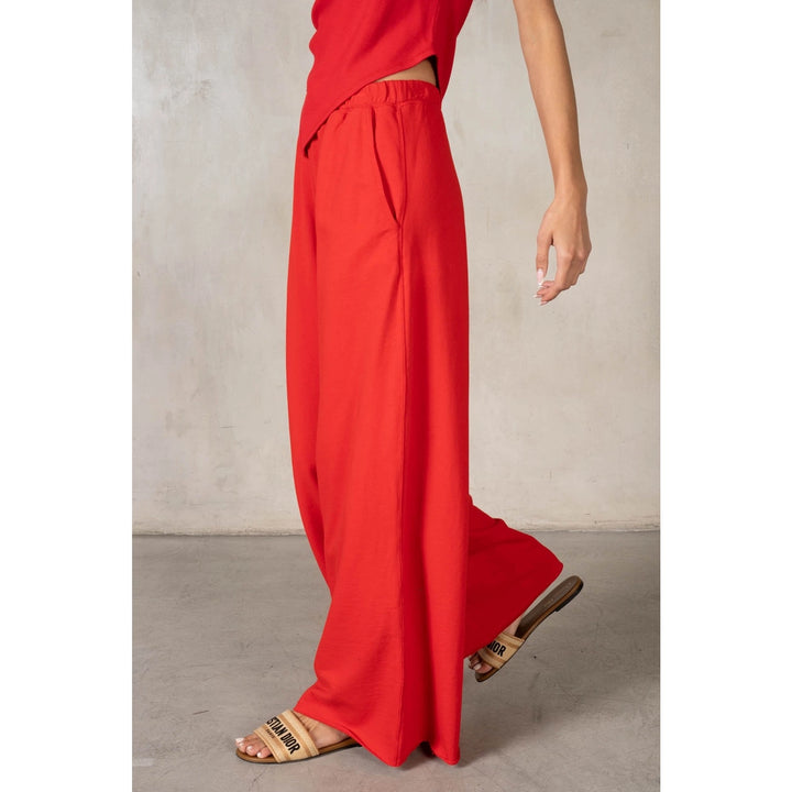 Person wearing red pants and sandals on a neutral background