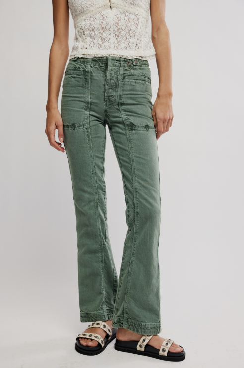 Person wearing green pants and a white top on a plain background