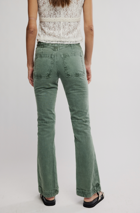 Person wearing green flared jeans on a white background