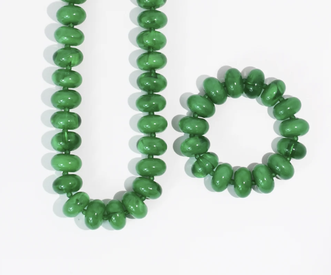 Matching green bead necklace and bracelet sitting on white background