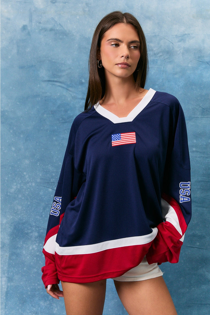 Woman wearing a navy blue long-sleeve shirt with USA flag design on a textured blue background