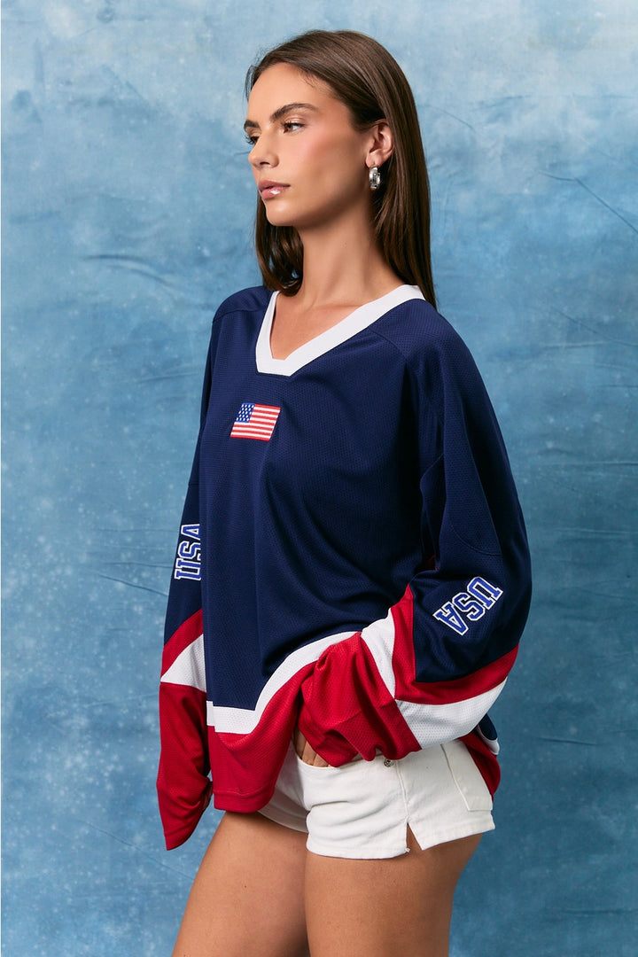 Woman wearing a USA-themed sweatshirt against a blue textured background
