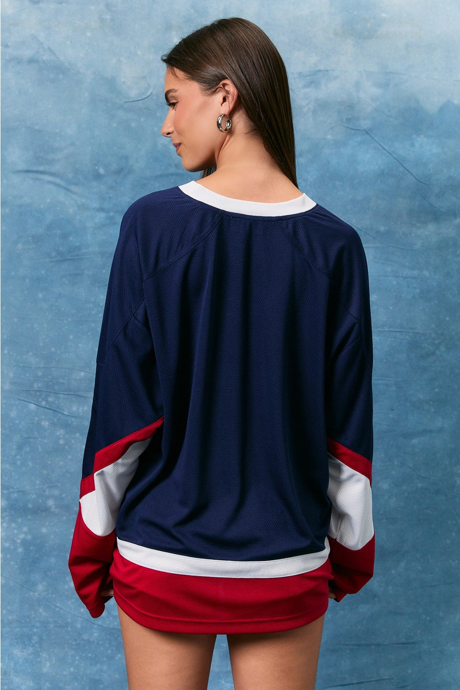 Person wearing a navy blue, red, and white sweater with a textured blue background
