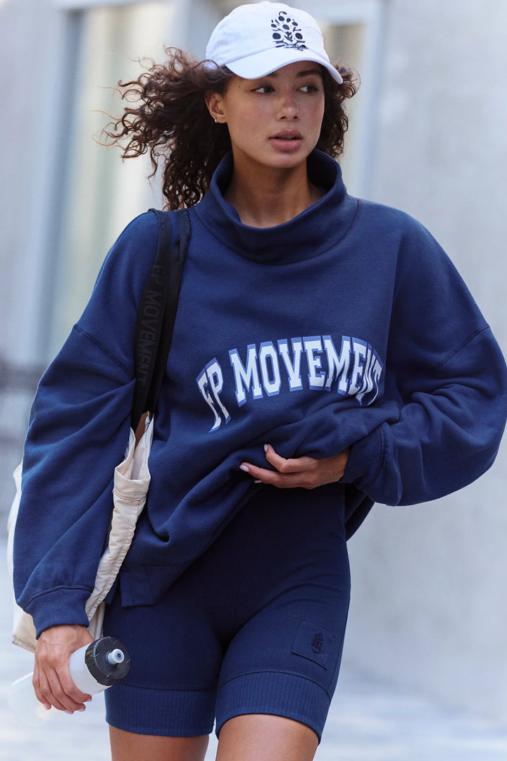 Woman wearing navy mock neck sweatshirt with &