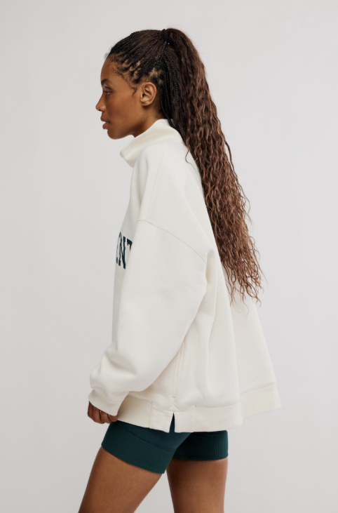 Woman wearing oversized ivory sweatshirt with green shorts