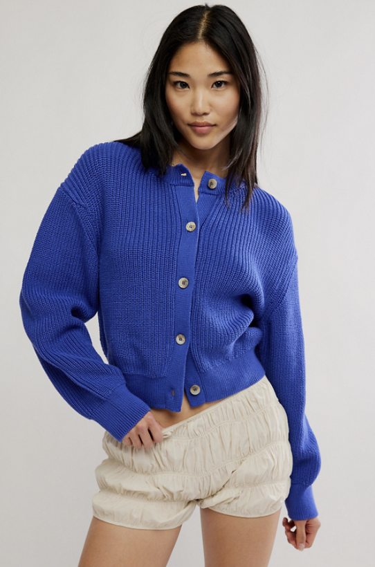 Woman wearing blue sweater and tan shorts on white background