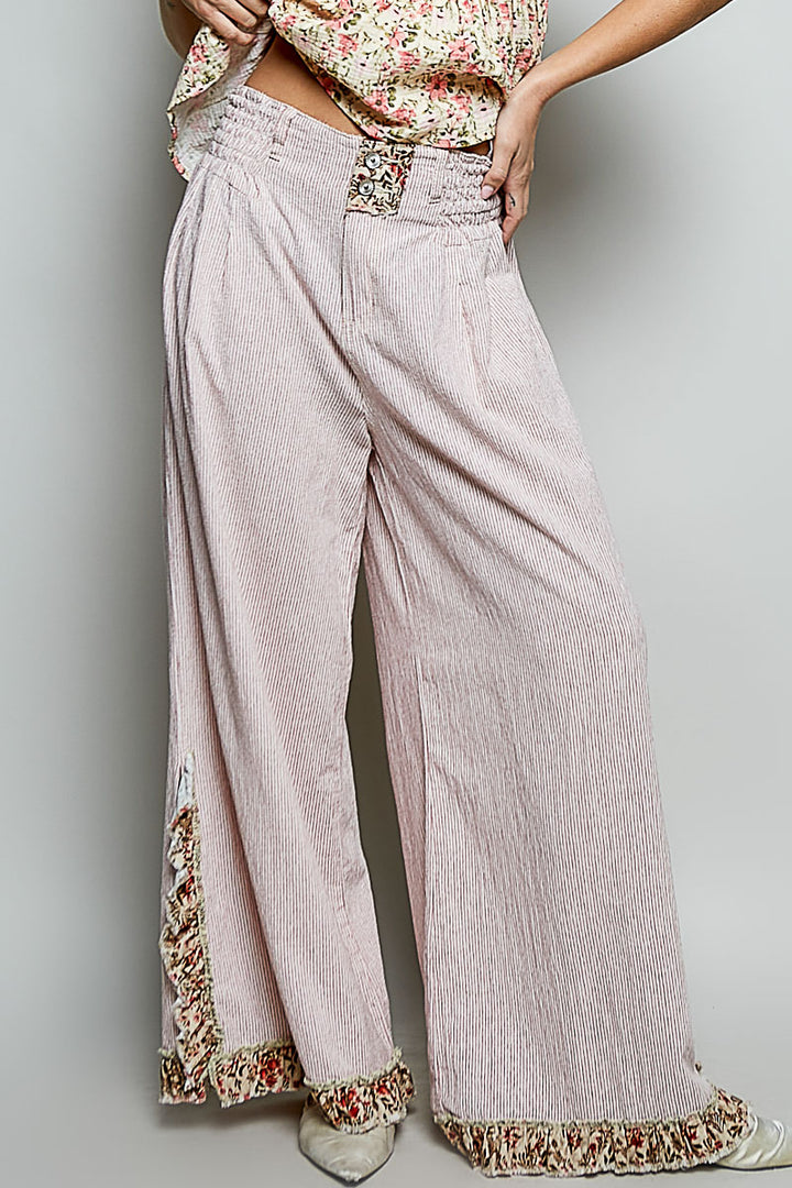Light pink pants with floral lace trim on a plain background