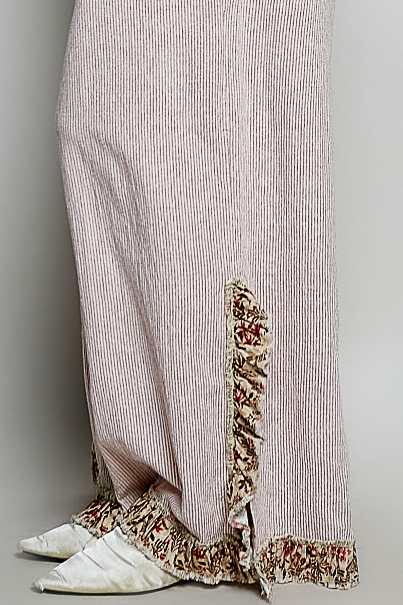 Striped pants with floral hem and white shoes on a gray background