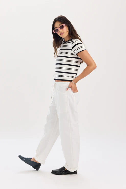 Woman wearing a black and white striped shirt and white pants on a white background