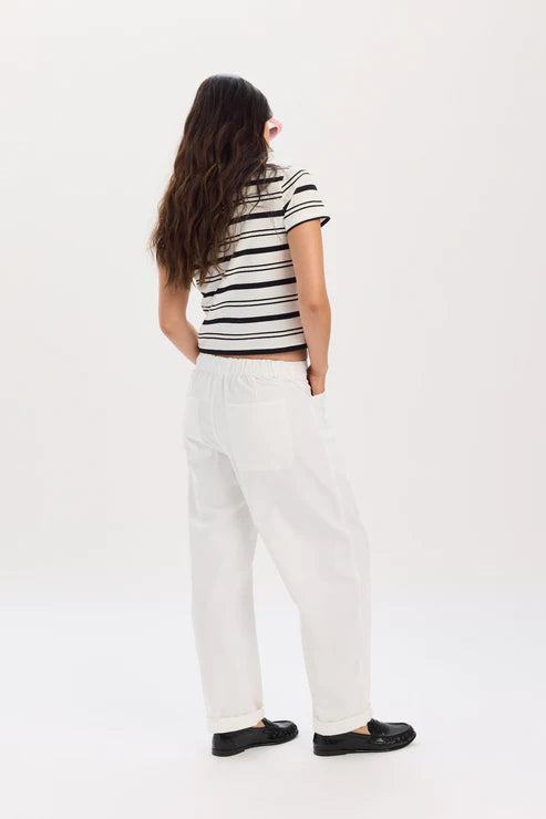 Person wearing a black and white striped shirt and white pants on a white background