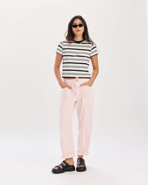 Woman wearing a black and white striped shirt and pink pants on a white background