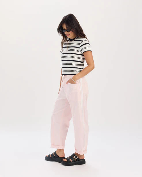 Person wearing a striped shirt and pink pants on a white background