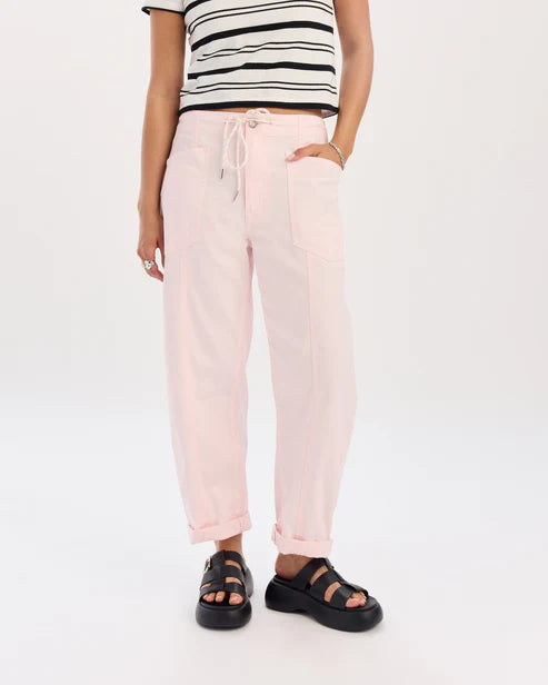 Person wearing light pink jogger pants and a striped top on a white background