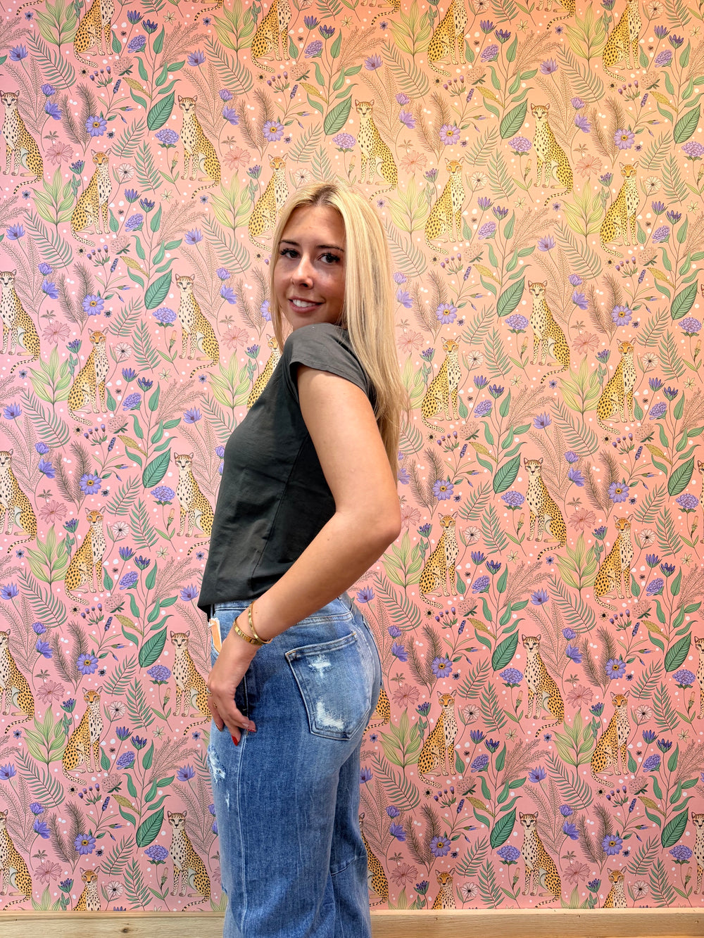 Woman wearing black tee shirt and jeans on pink floral background