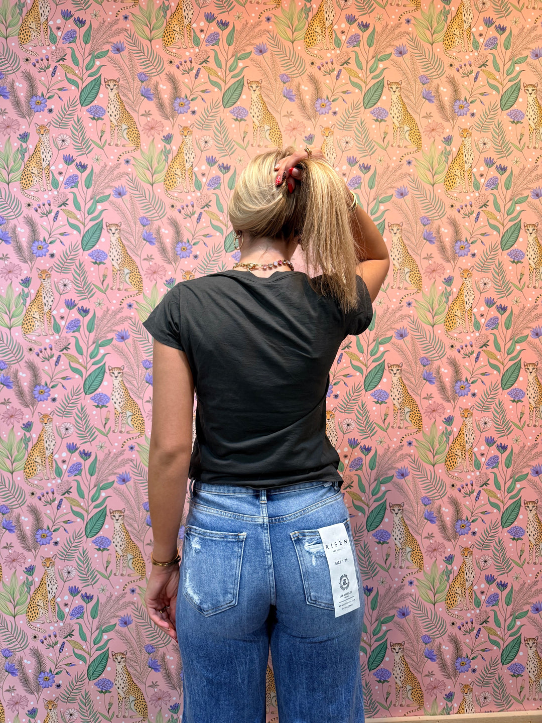 Person wearing black tee and jeans on pink floral background