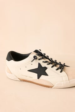 Beige sneaker with black star and laces on a beige background