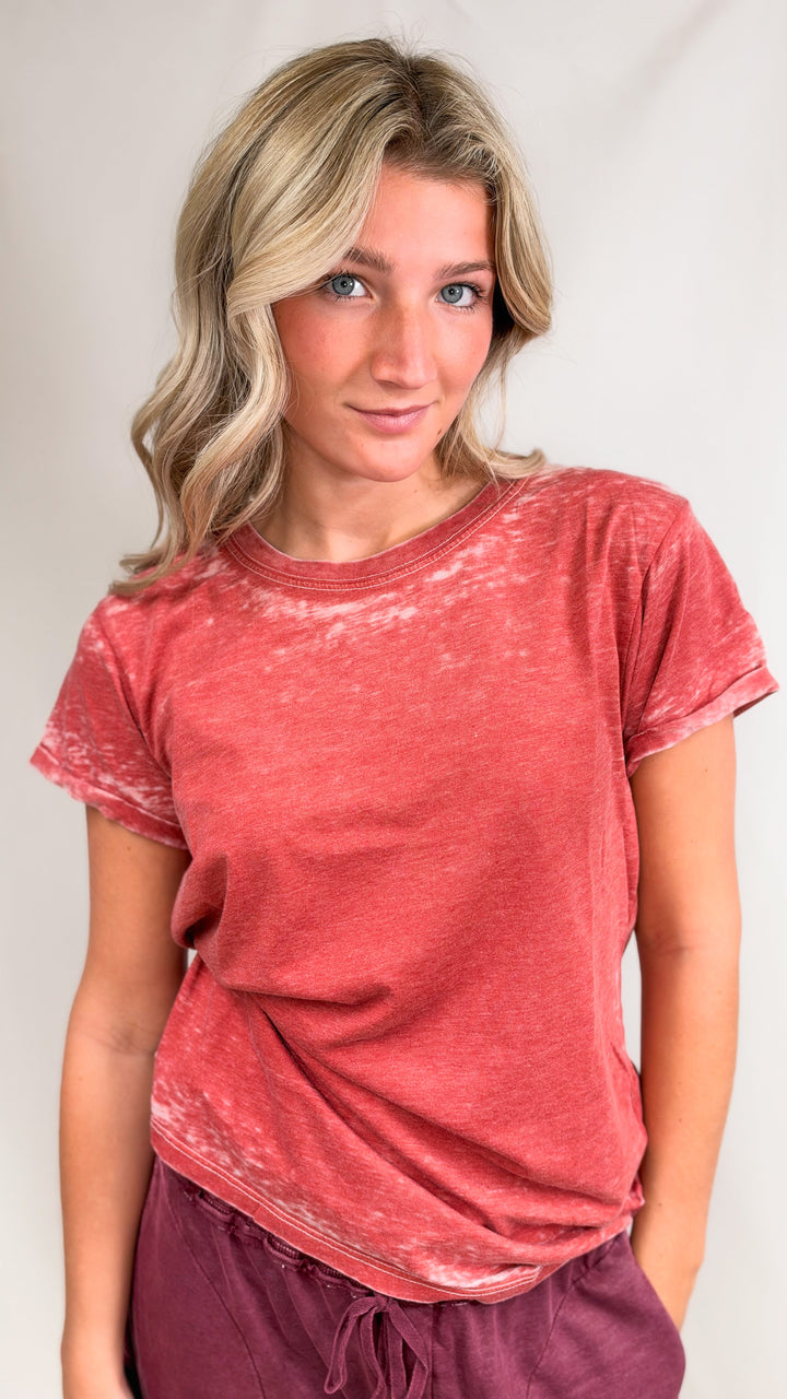 Woman wearing red tee with maroon pants on plain background