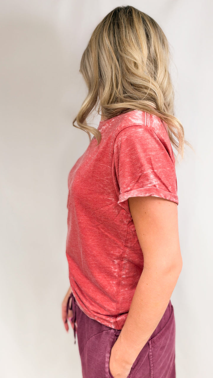 Woman shown from side view wearing red tee and maroon pants on plain background
