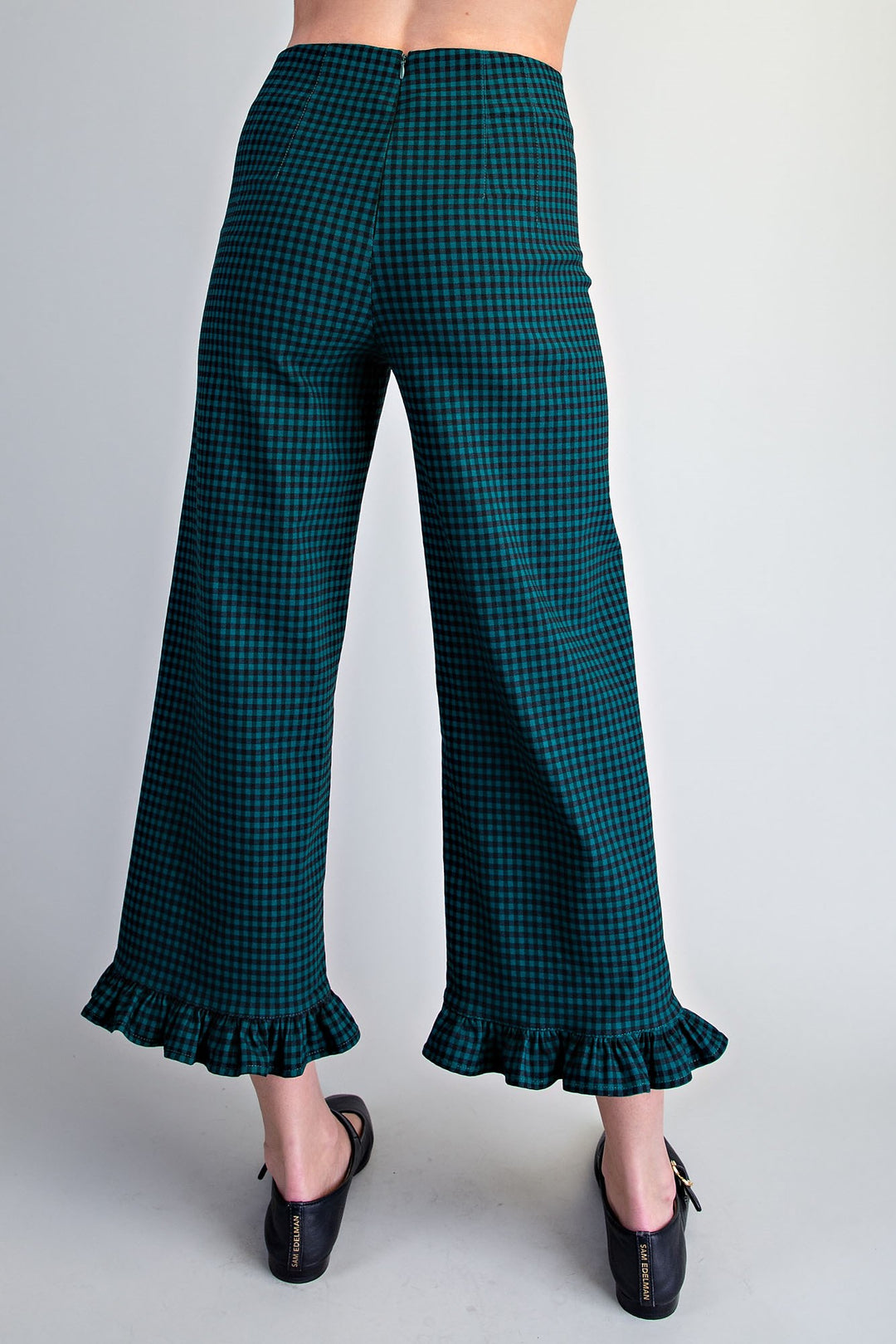 A person shown from the back wearing dark teal and black gingham cropped wide-leg pants with ruffled hems, paired with black shoes, against a light gray studio background.