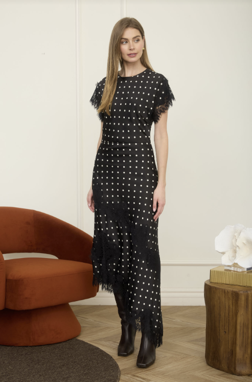 Woman wearing black and white polka dot satin dress with lace detail standing in living room setting