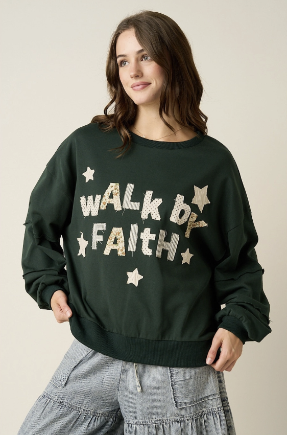 A woman wearing a dark forest green crewneck sweatshirt with &