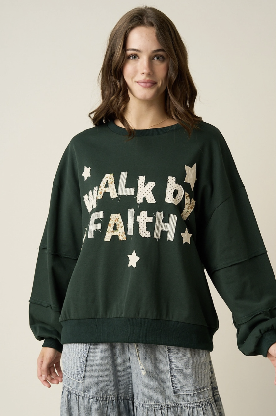 A woman wearing a dark forest green crewneck sweatshirt with &