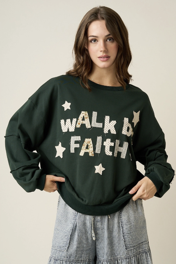 A woman wearing a dark forest green crewneck sweatshirt with &