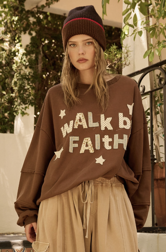 Woman wearing brown sweatshirt with &