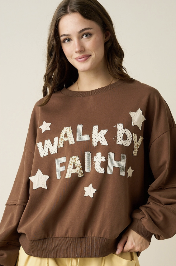 A woman wearing a brown crewneck sweatshirt with &