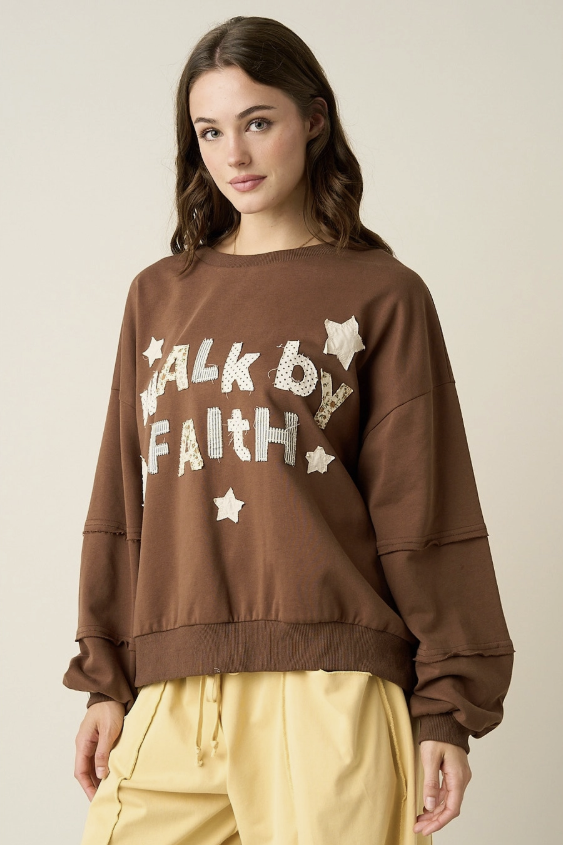 A woman wearing a brown crewneck sweatshirt with &