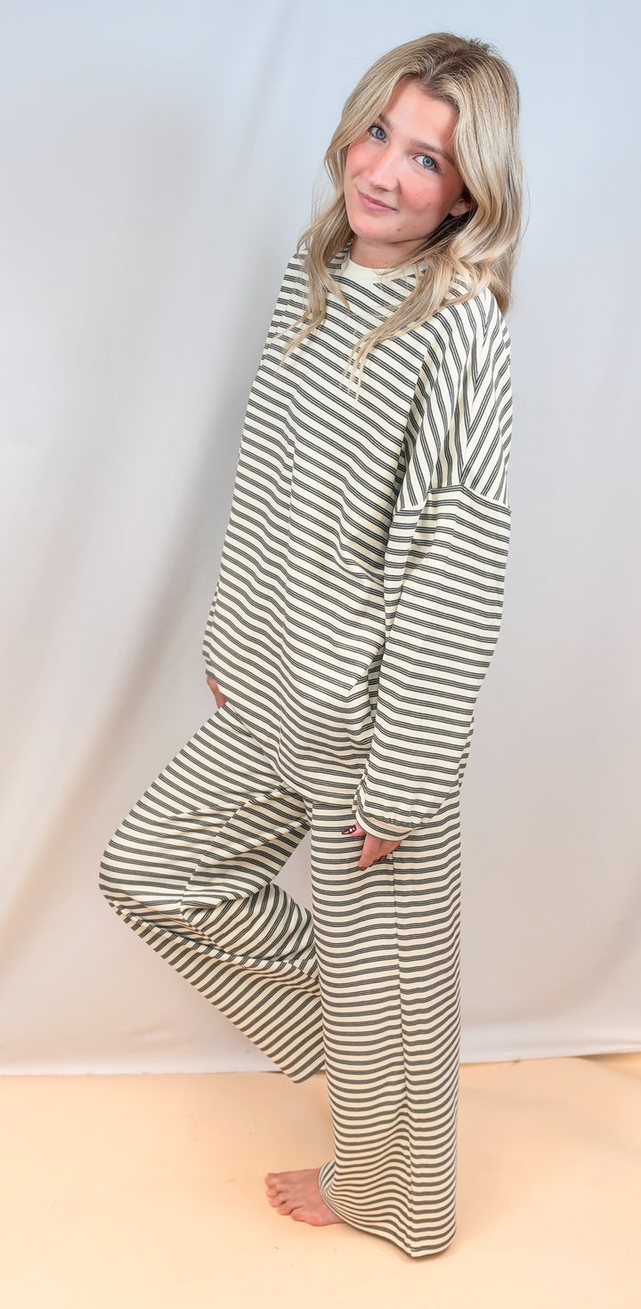 Woman shown from side view wearing cream stripe matching set on plain background