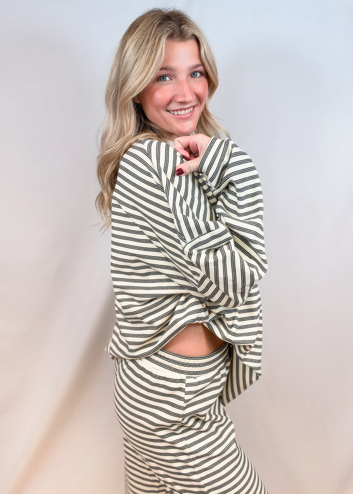 Woman shown from side view wearing cream stripe matching set on plain background