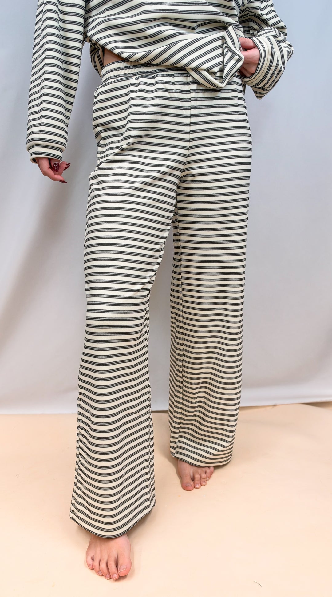 Woman shown from waist down wearing cream stripe matching set on plain background