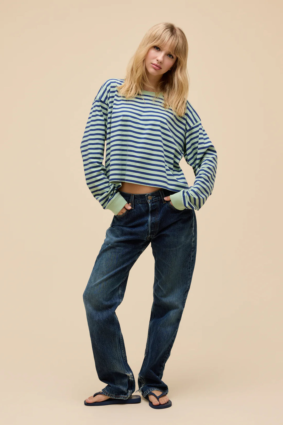Woman wearing a striped sweater and jeans on a beige background