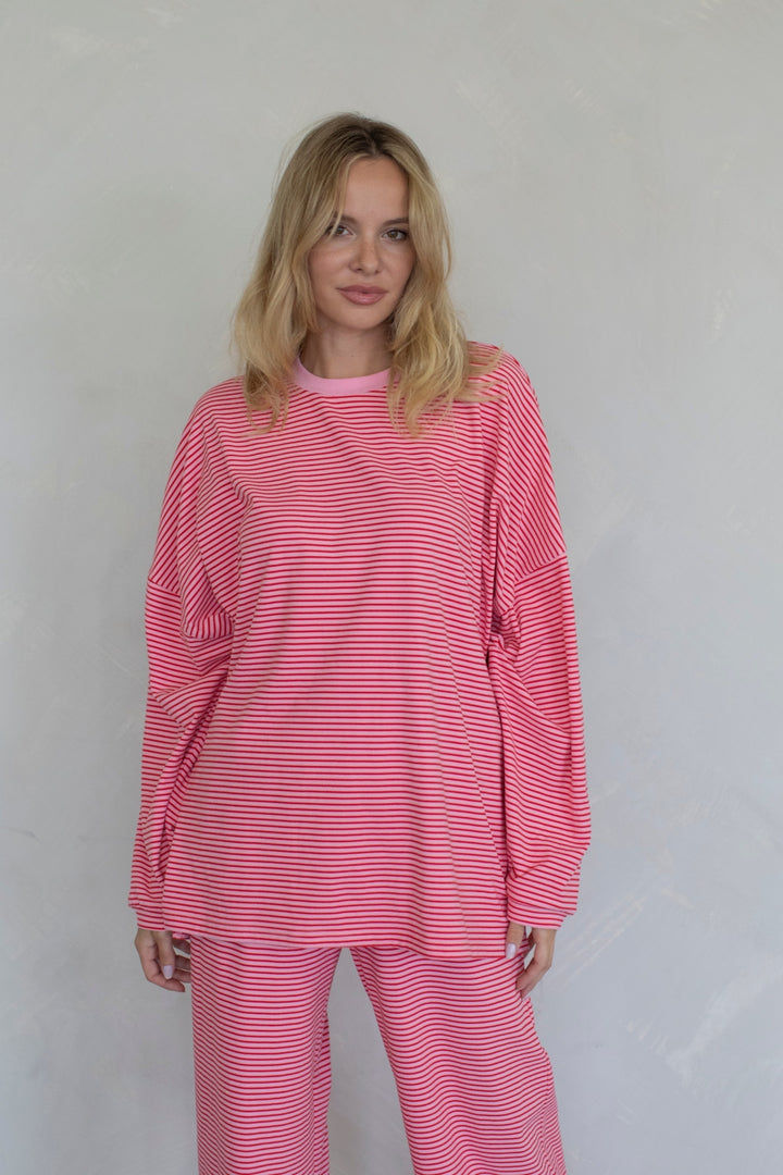 Woman wearing a pink and white striped outfit against a plain background