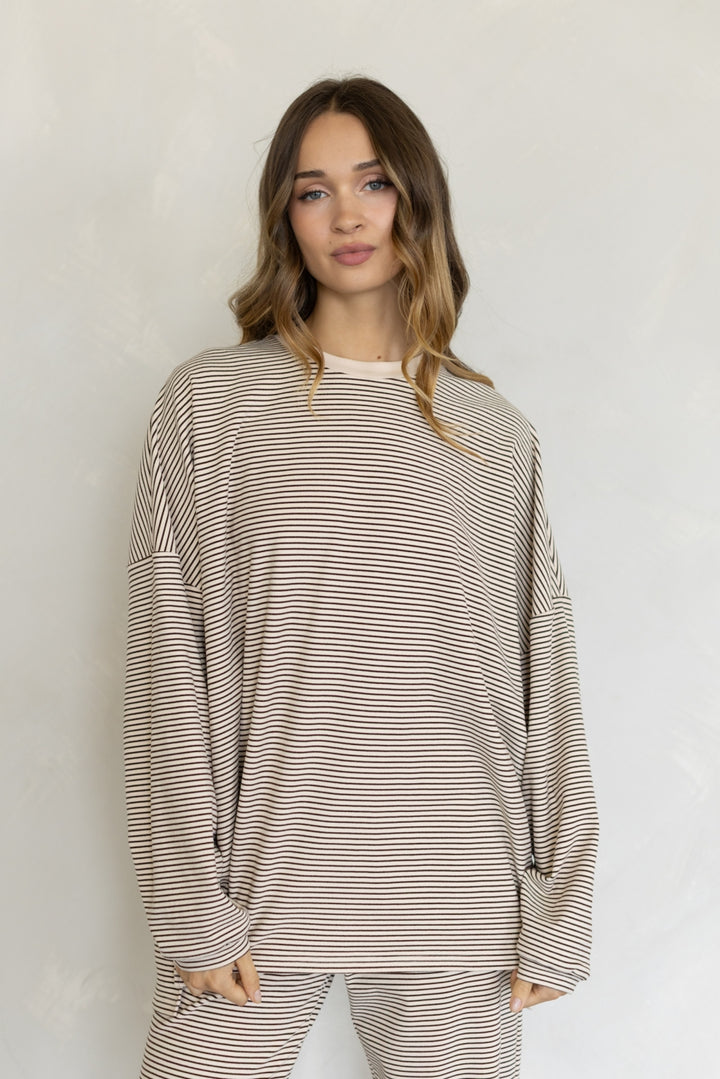 Woman wearing a striped long-sleeve top and pants against a plain background