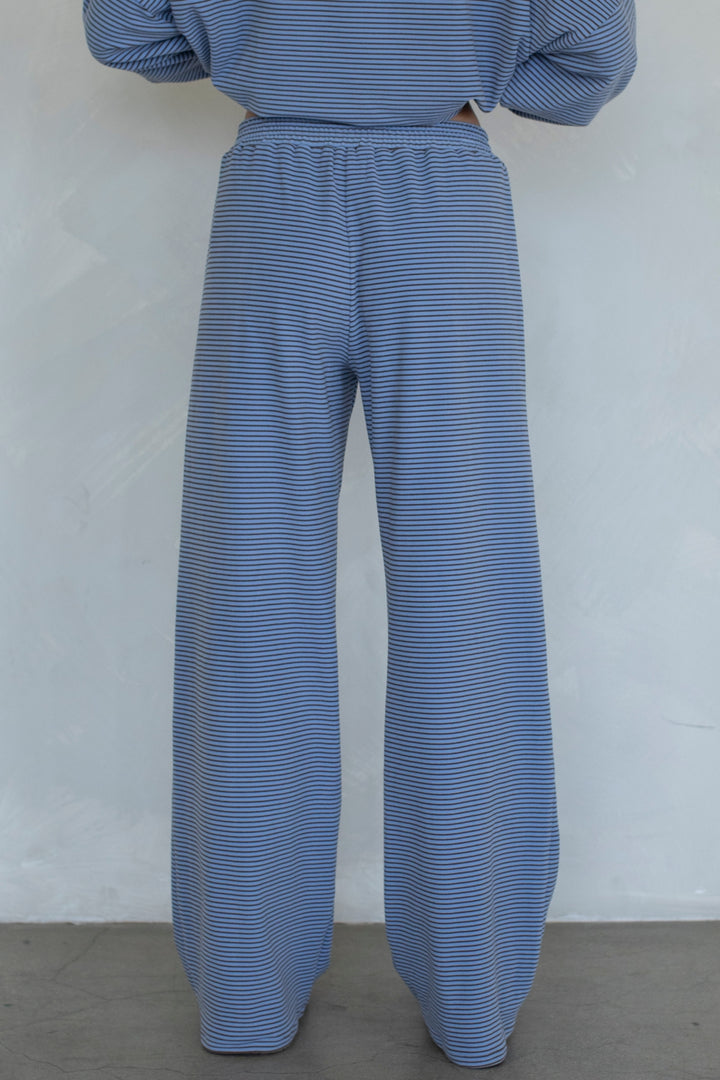 A person shown from the back wearing loose, wide-leg pants and a matching striped top. The fabric has a fine blue and white stripe pattern.