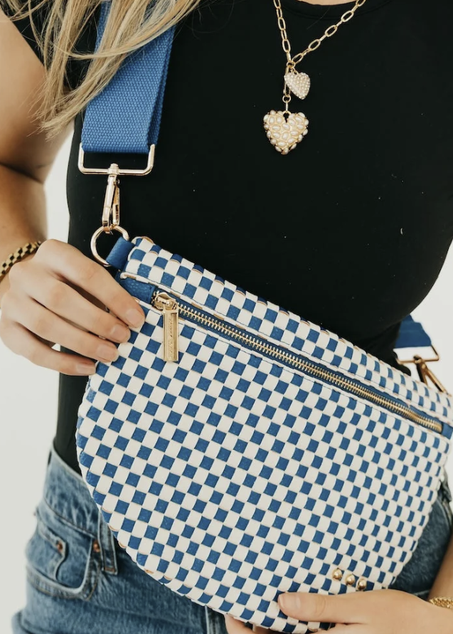 Woman wearing royal blue checkered bum bag with black shirt on white background