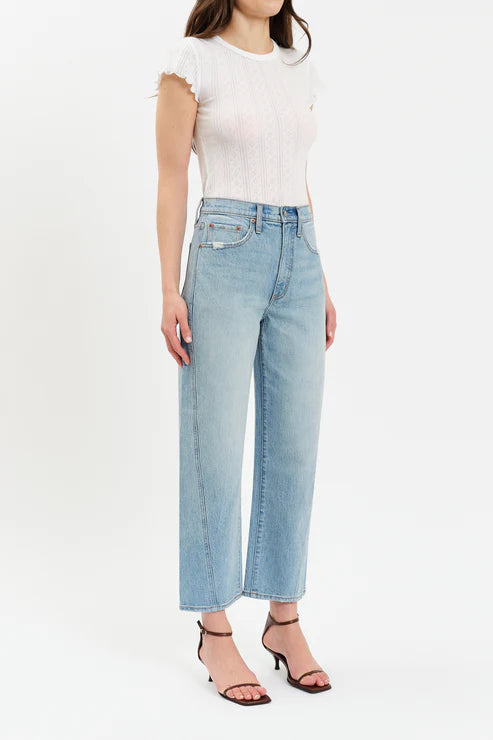 Woman wearing light blue jeans and a white top on a white background