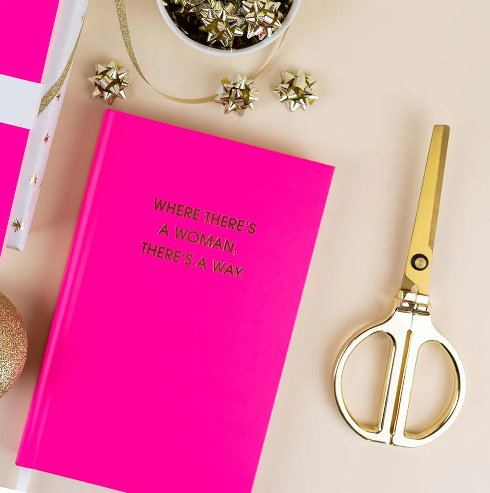 Pink notebook with text and gold scissors on a light background