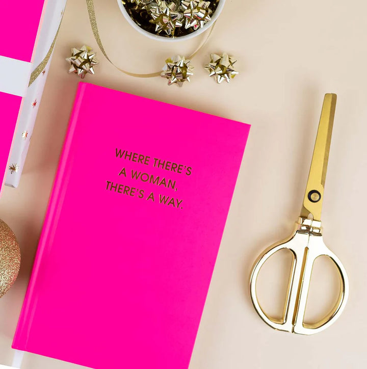 Pink notebook with text and gold scissors on a light background