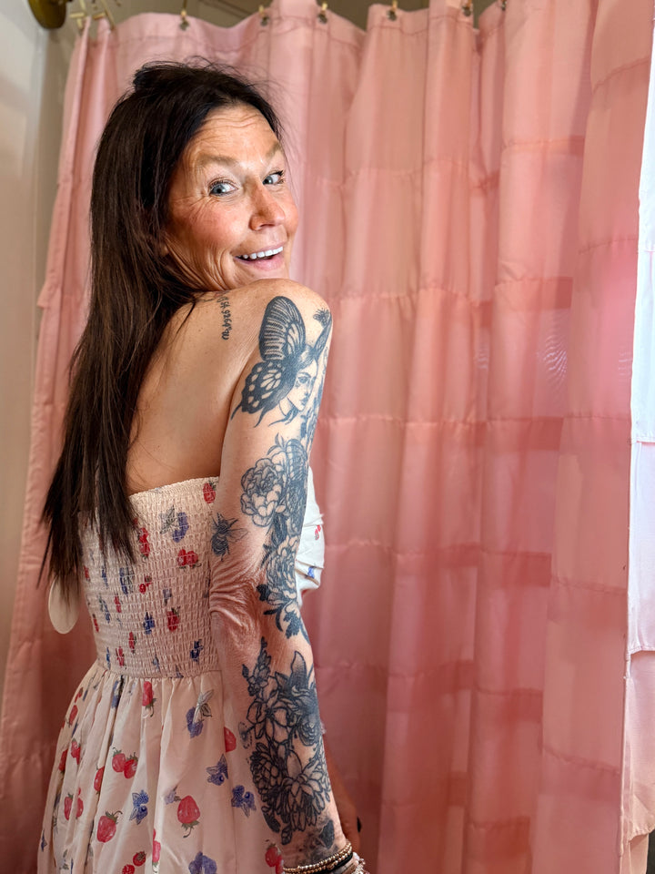 Woman with tattoos on her back standing in front of a pink shower curtain.