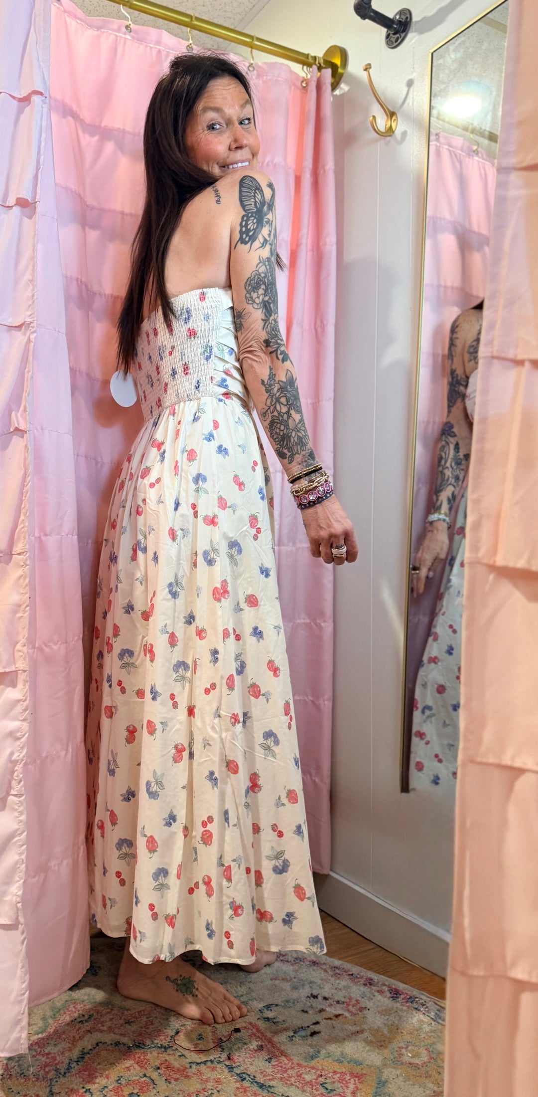 Woman in a floral dress standing in front of a pink shower curtain.