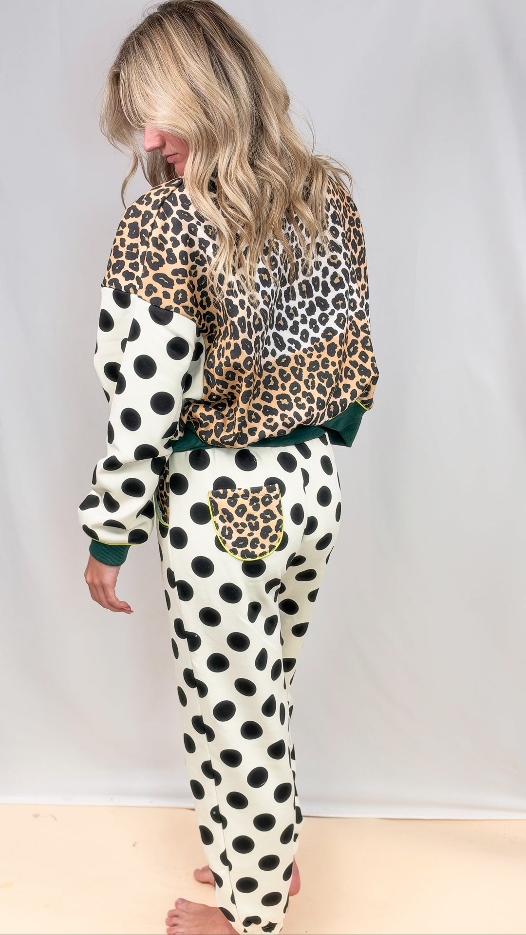 Woman shown from back wearing matching sweatsuit with leopard print and polka dots on plain background