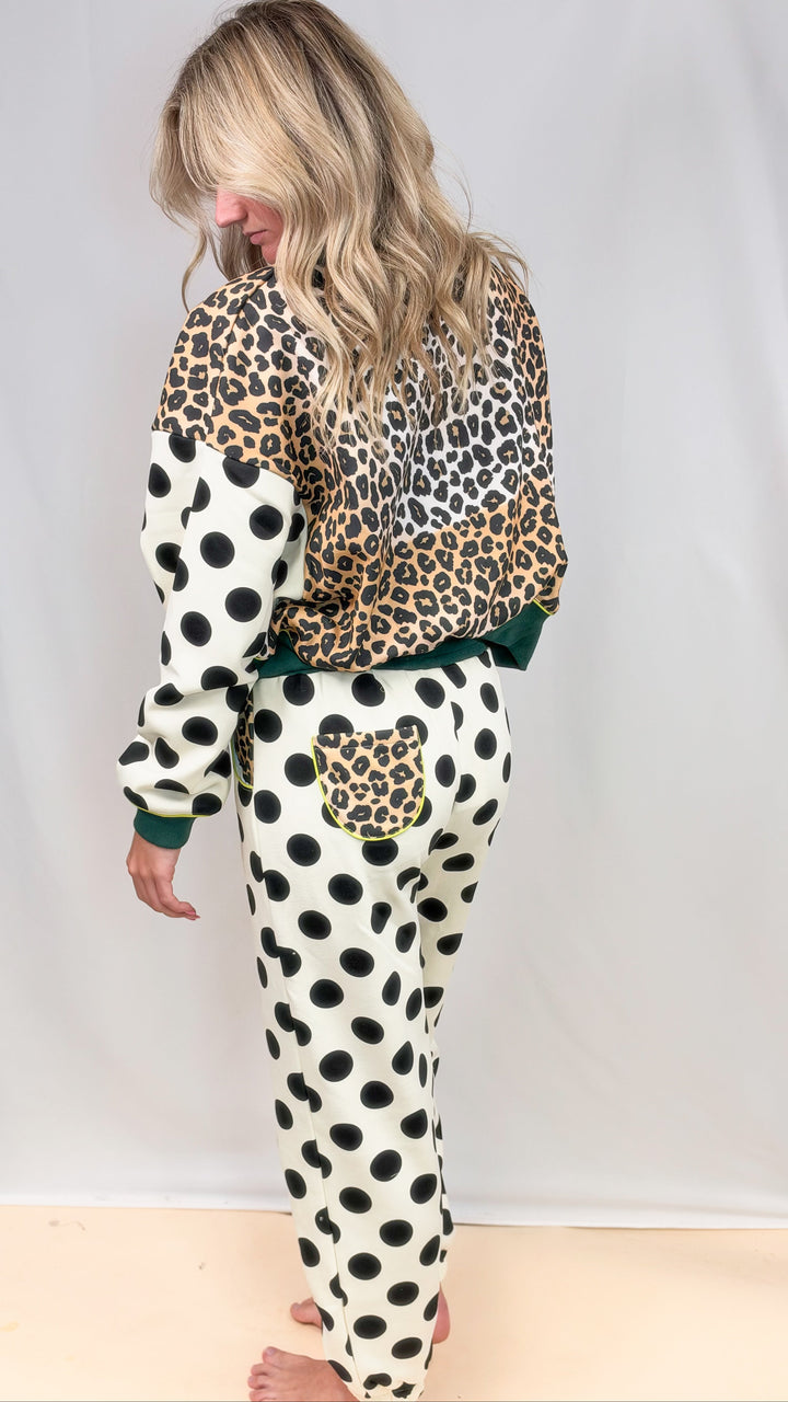 Woman shown from back wearing matching sweatsuit with leopard print and polka dots on plain background