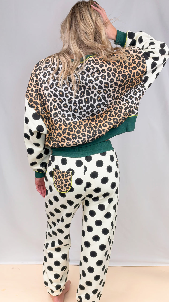 Woman shown from back wearing matching sweatsuit with leopard print and polka dots on plain background