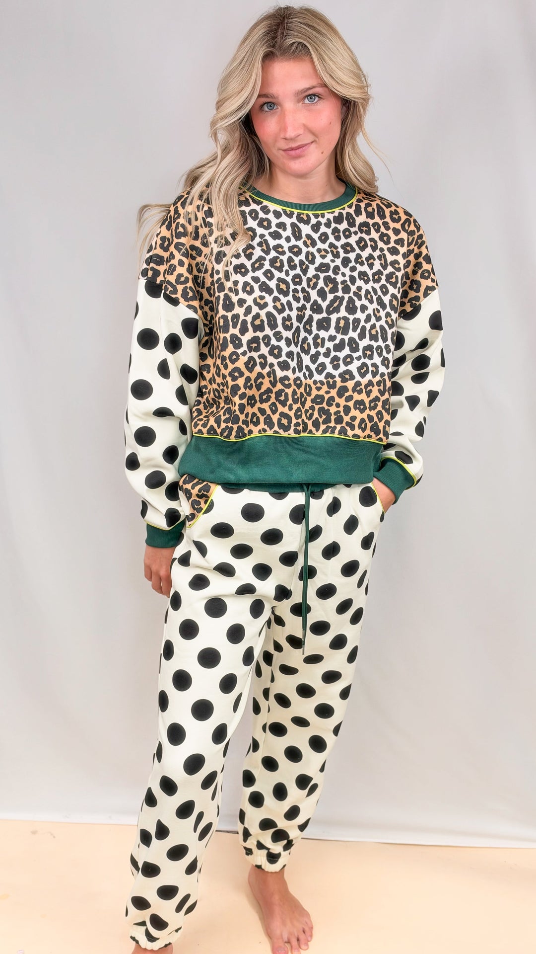 Woman wearing matching sweatsuit with leopard print and polka dots on plain background