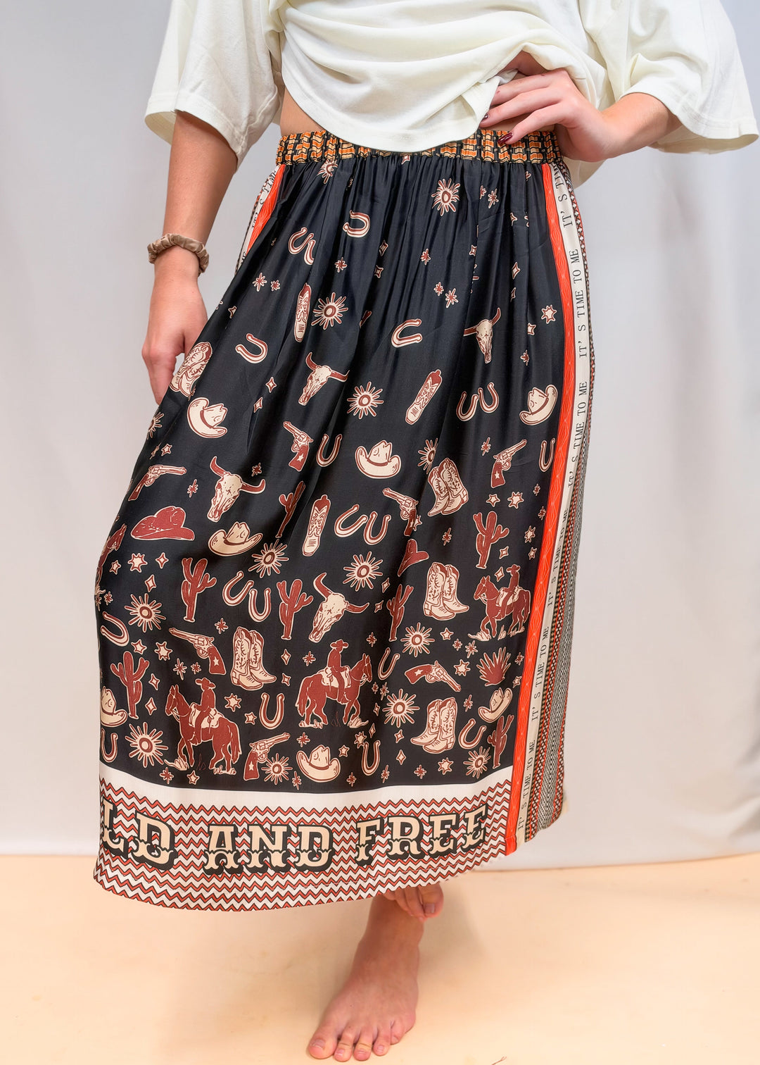 Woman wearing white tee and scarf skirt with rodeo motif on plain background